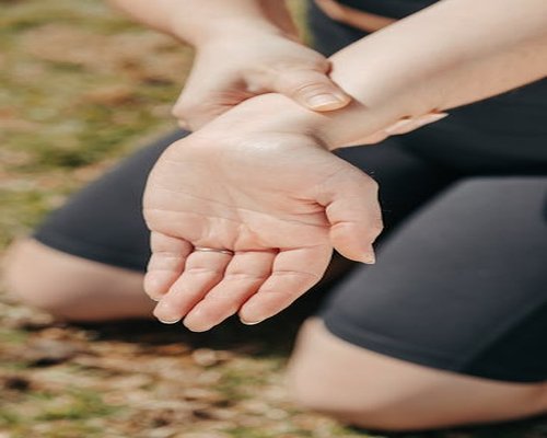 close up of hands doing gentle wrist stretch at desk